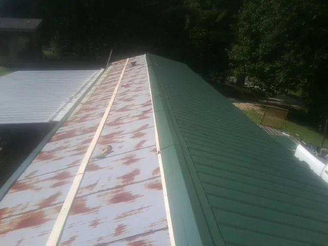 Old rusted panels beside newly installed green metal roofing — Wind Damage Roof Repair by Roofing Brothers in Lithia Springs