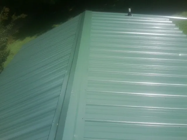 New green metal panels meeting at the ridge of a roof — Flat Roof Repair work by our crew in Lithia Springs