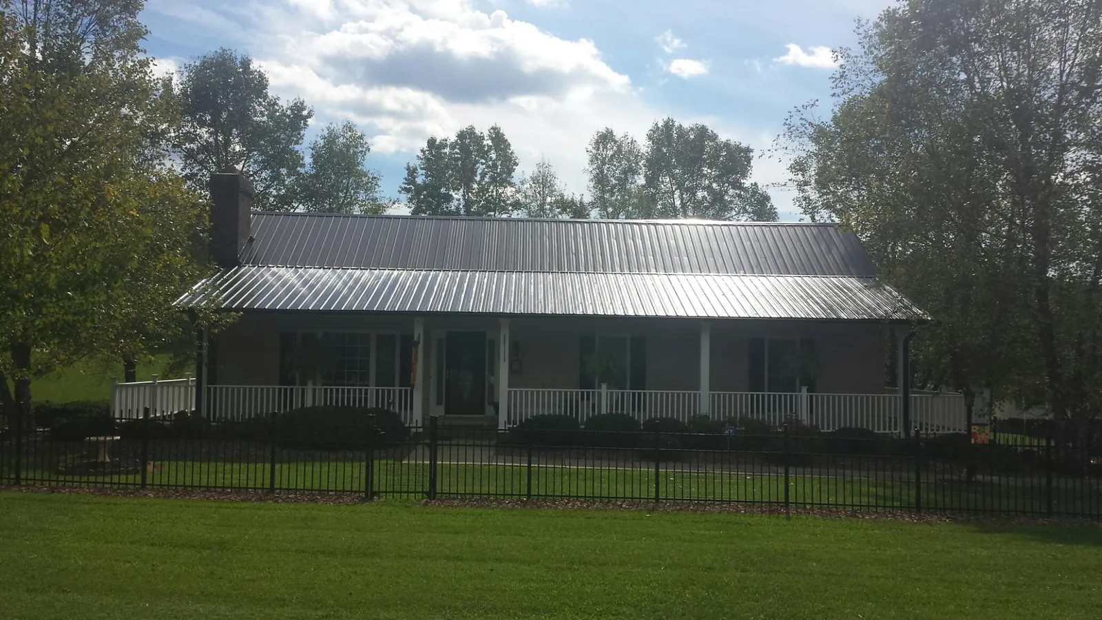 Gray metal roof on a brick ranch with a full width front porch — Gutter Guard Installation work by our crew in Lithia Springs