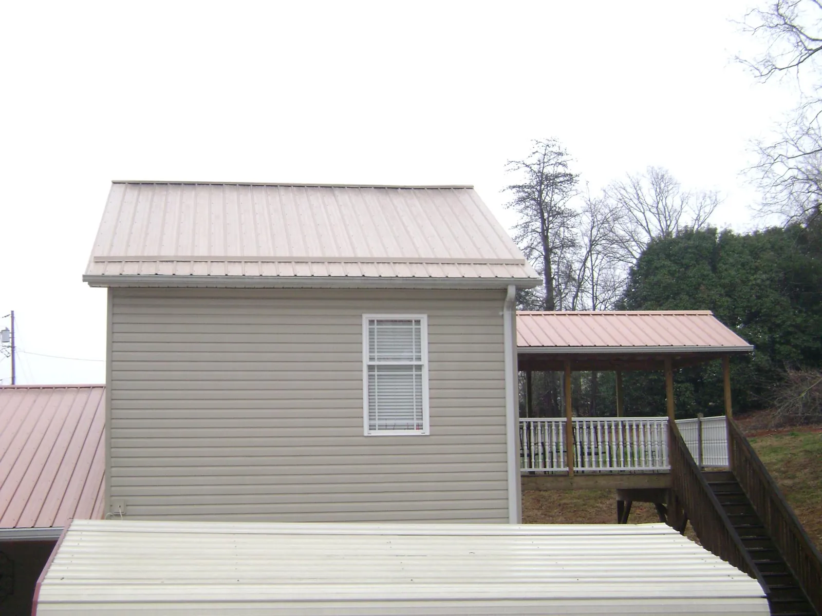 Tan metal roofs on a two story addition and attached porch, from a Roof Replacement job in Lithia Springs