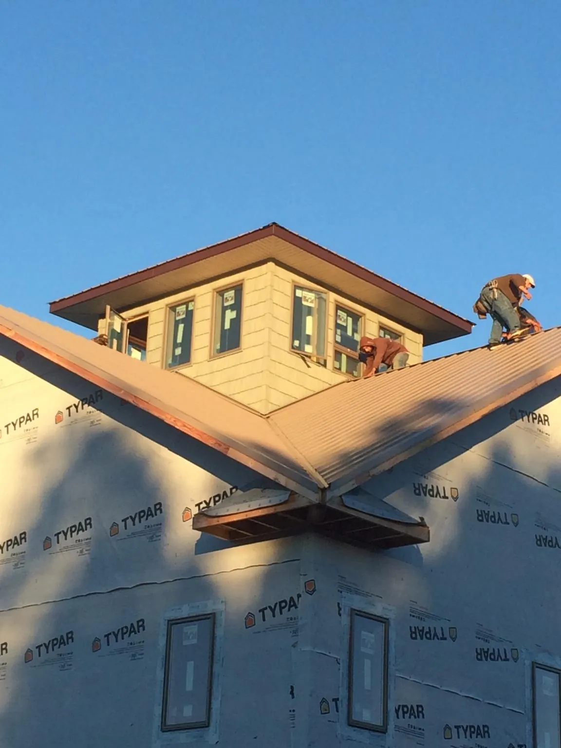 Roofers working around a rooftop cupola on a new metal roof at sunset — Roof Waterproofing in Lithia Springs by Roofing Brothers